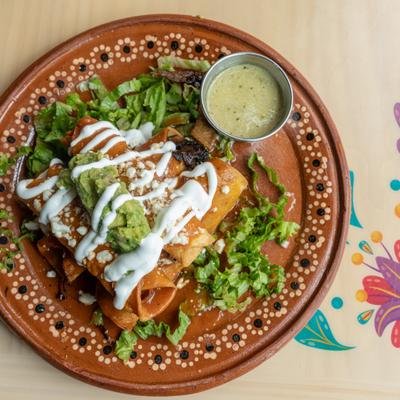 Flautas served with lettuce, guacamole, drizzle of crema and a dipping sauce.