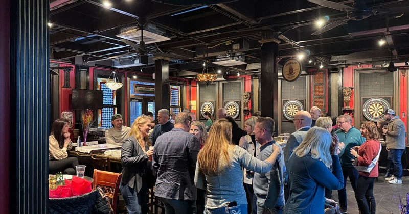 A lively gathering inside, features people socializing and enjoying drinks