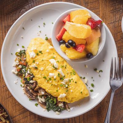 Veggie and mushroom omelet with fruit bowl, overhead view