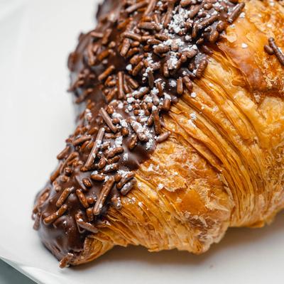 Chocolate croissant with chocolate sprinkles and powdered sugar.