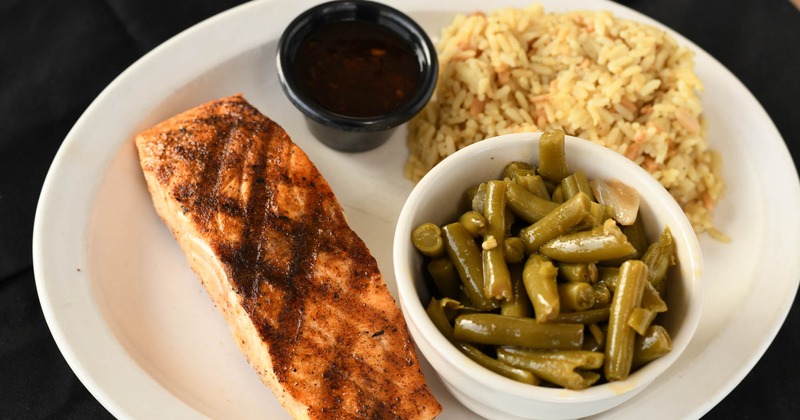 Grilled salmon with greens beans, rice, and sauce on the side