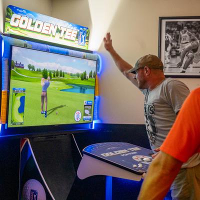 Person playing an arcade golf game inside a venue.