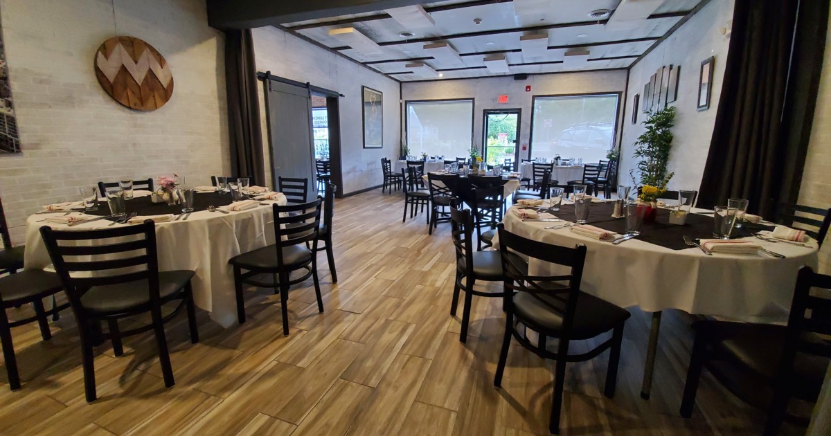Restaurant tables set with white tablecloths, neatly arranged cutlery, and glasses