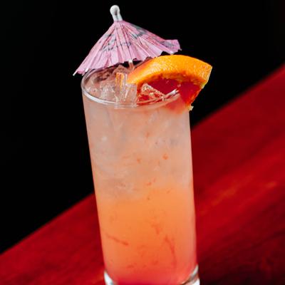 Paloma cocktail with grapefruit slice and paper umbrella garnish.