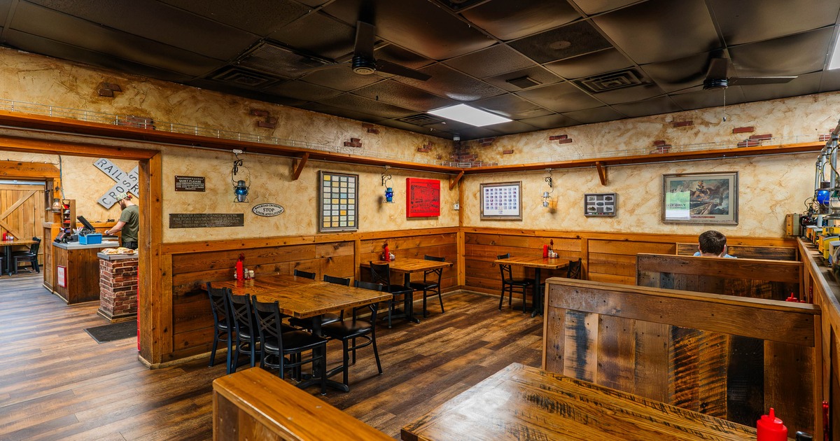 Interior view of a rustic restaurant featuring wooden furniture, booth seating