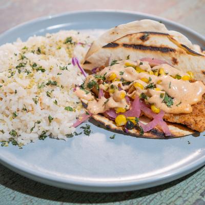 Fish tacos with pickled red onions, corn, a creamy chipotle sauce and a side of rice.