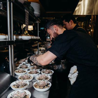 Two chefs preparing shrimp appetizers.