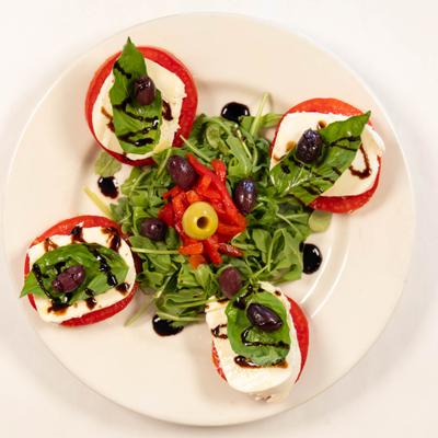 Caprese salad with mozzarella, tomato, basil, olives and balsamic vinegar glaze.