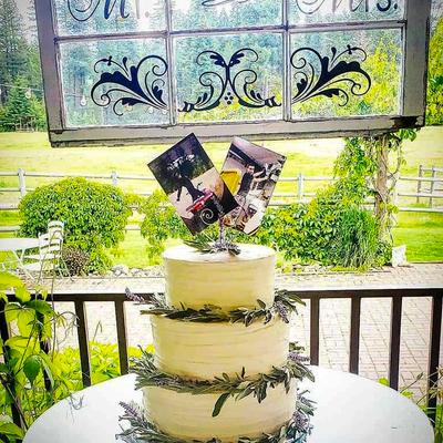 Three-tier white wedding cake  set on a veranda, lush greenery in the background.