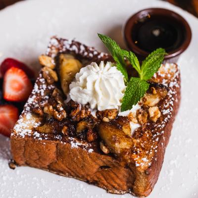 French toast topped with whipped cream, caramelized bananas, nuts, and powdered sugar.