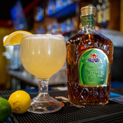 Margarita cocktail on a bar counter next to a bottle of liquor.