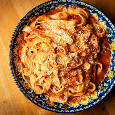 A decorative plate holds Fettuccine Bolognese Pasta.