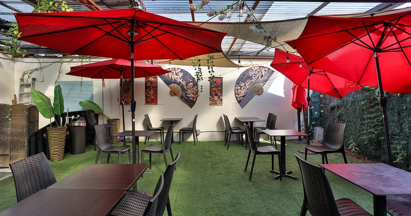 Covered patio with tables, chairs and red parasols