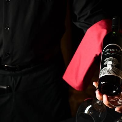 A sommelier holding a bottle of wine and two wine glasses.