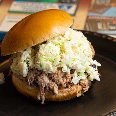 Chopped BBQ sandwich topped with creamy coleslaw on a bun.