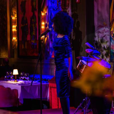 Singer performing during the show with colorful paintings in the background.