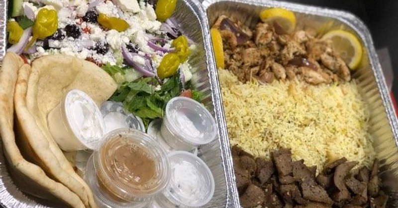 Trays of food featuring a fresh salad and pita bread, gyro beef and chicken, and rice