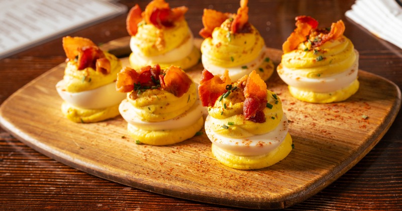 Deviled eggs topped with crispy bacon, fresh chives and dusting of smoked paprika