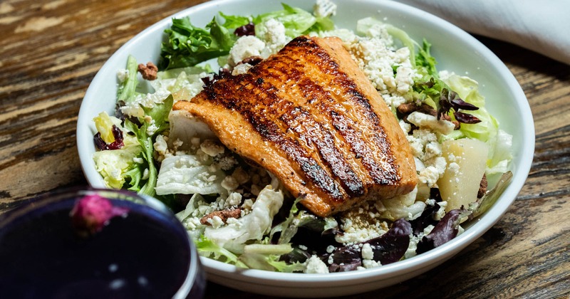 Blackened salmon fillet served on a bed of mixed greens and crumbled cheese