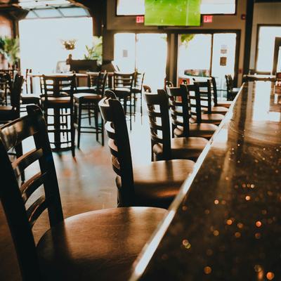 Bar counter and chairs with seating area in the background.