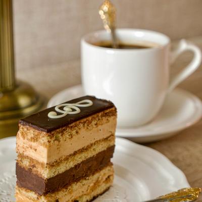 Layered cake slice served with a cup of coffee.