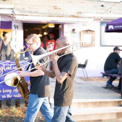 Exterior, a saxophonist and trombonist playing.