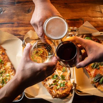 People toasting with drinks over a table with food.