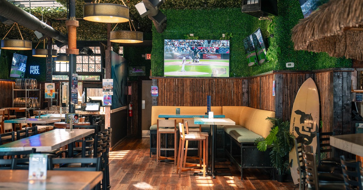 Sports bar interior with TVs, booth seating, and surf-themed decor