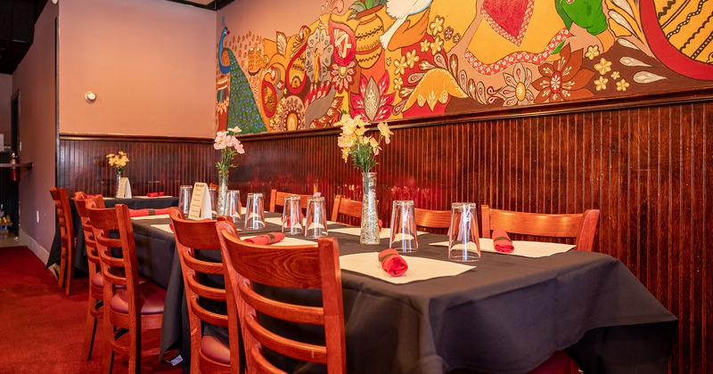 Inside, tables setting and floral decoration, mural art on a wall