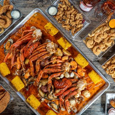 Large tray of a Cajun-style seafood boil alongside other dishes.