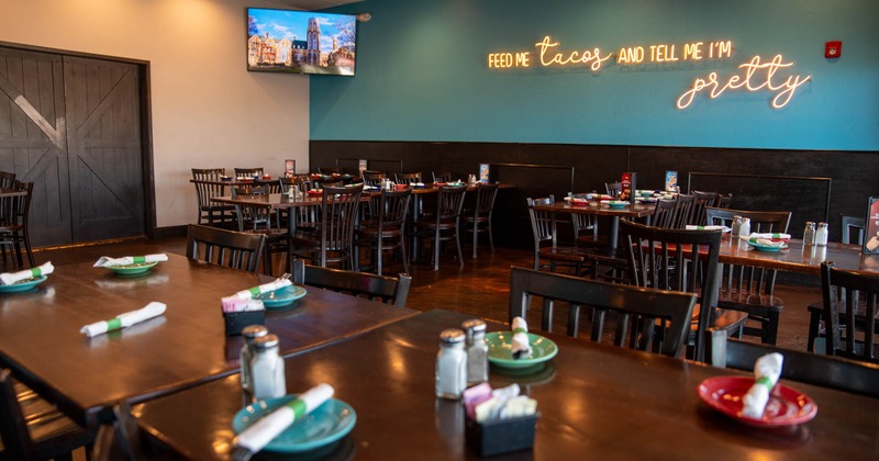 Interior, dining area, tables for four, six and eight, neon sign writings on the wall