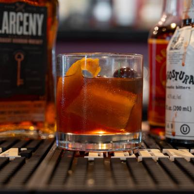 Old Fashioned cocktail flanked by a bottle of bourbon and bitters.
