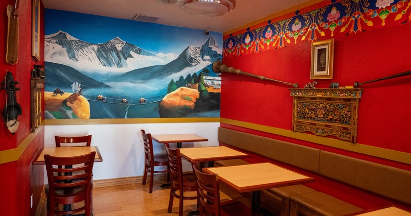 Interior, dining area, long banquette bench with wooden top tables and chairs, Himalayas mural