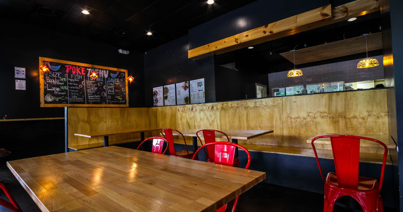 Interior, long corner bench with tables and red chairs, blackboard with menu on the wall