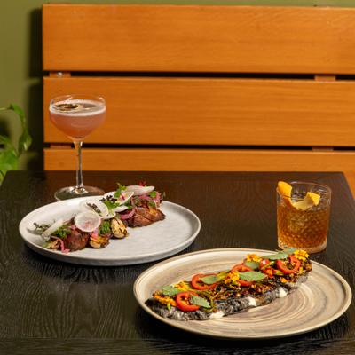 Two different entrees served on the table with cocktails.