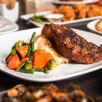 Smokehouse Manhattan Striploin on a  plate with mashed potatoes and vegetables.