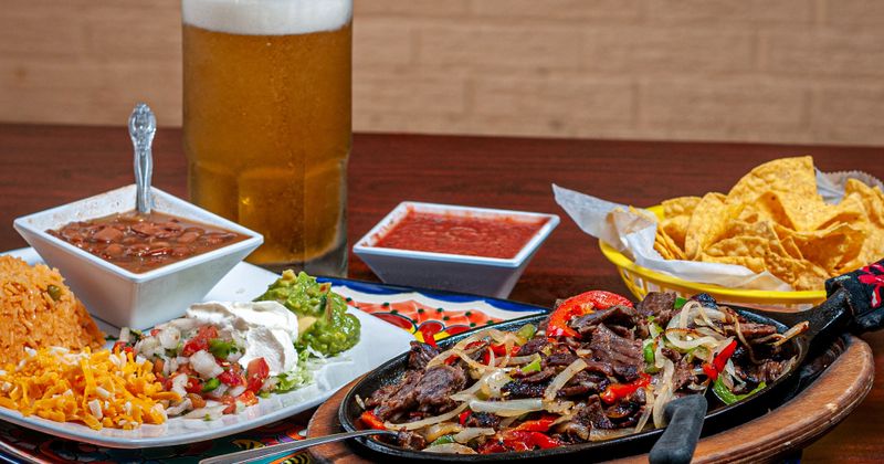 Fajitas served with different side dishes and beer