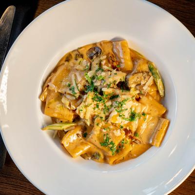 Paccheri pasta in a creamy mushroom sauce, topped with herbs and cheese.