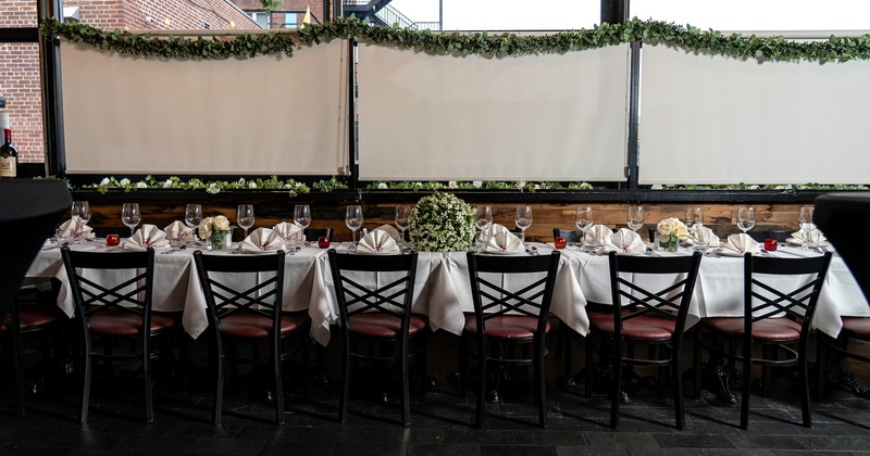 An elegant dining setup in an enclosed patio space with a long set table