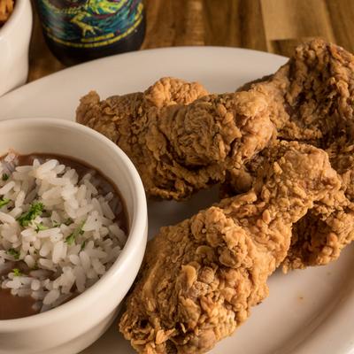 Fried chicken served alongside a bowl of rice and beans.