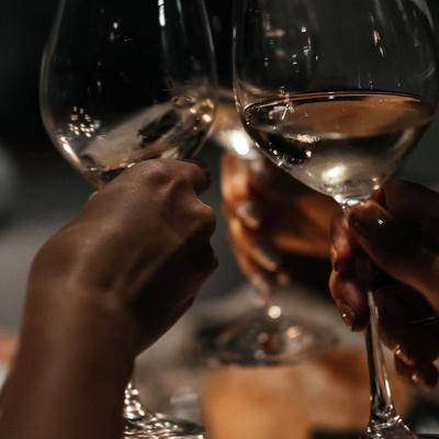 Three people raising their wine glasses in a toast, hand shot.