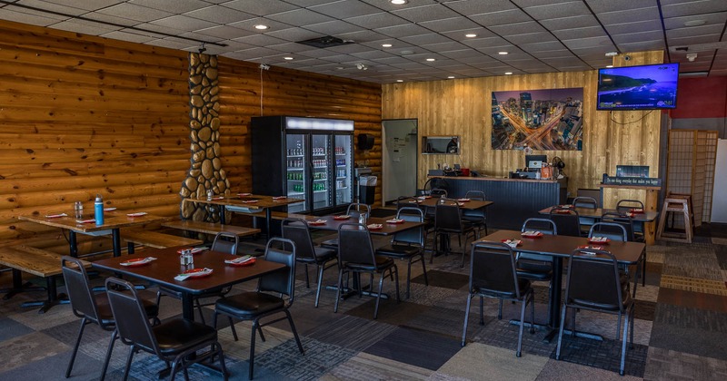 Interior, wood-paneled walls, tables set for dining, and a large refrigerator