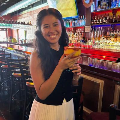 A smiling person holding a drink.