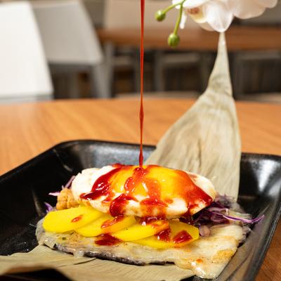 Drizzling a red sauce over the Buldak Taco on a table.