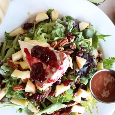 Warm Brie Cheese Salad, with mixed greens, raspberry vinaigrette, pecans, cranberries, and apples.
