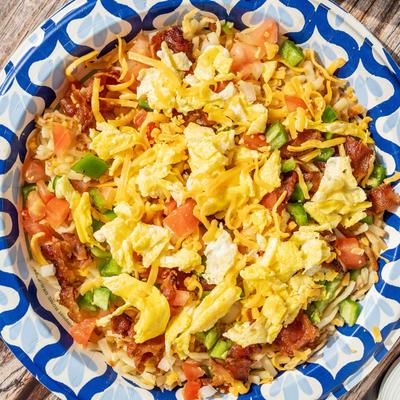 Hashbrowns, with scrambled eggs, bacon, American cheese, tomatoes, and scallions.