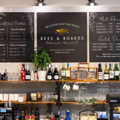 Wall menu, coffee machines, wall shelves with drinks, cups and glasses.