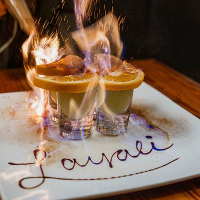 Shots on a white plate are set on fire, creating a dramatic presentation