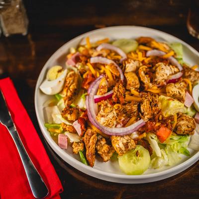 Chef salad, with chicken, lettuce, ham, tomato, cheese, onion, cucumber, egg, and bacon.