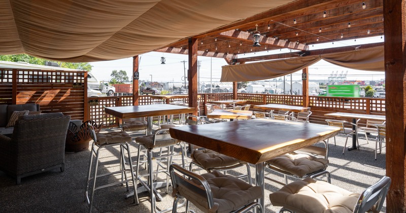 Outdoor dining area under a shaded canopy with wooden tables and chairs
